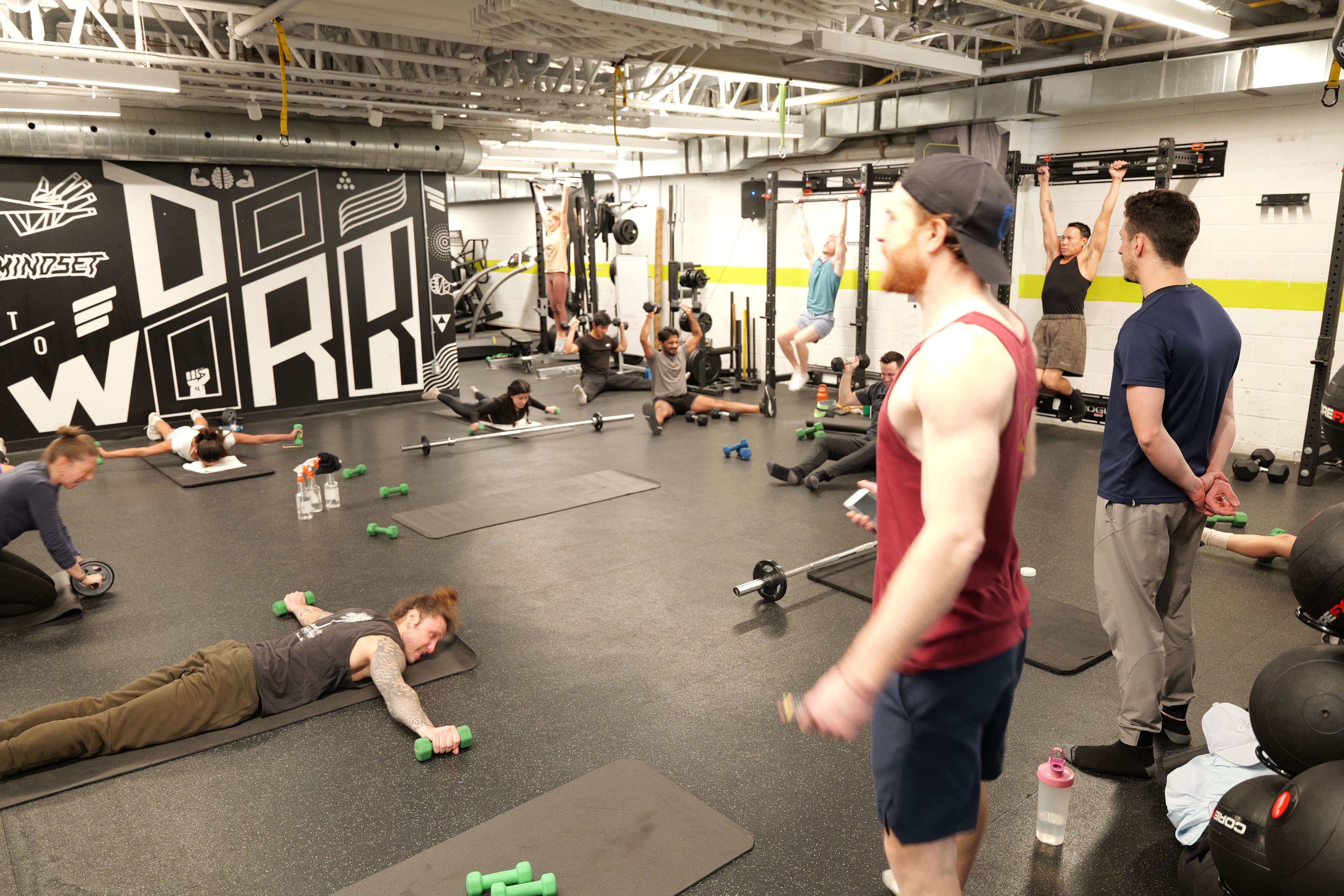 Full class in session at the gym — WORK mural in background